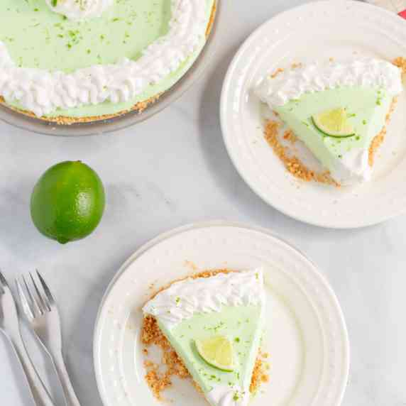 Slices of Key Lime Margarita Pie on white plates, fresh lime on the table