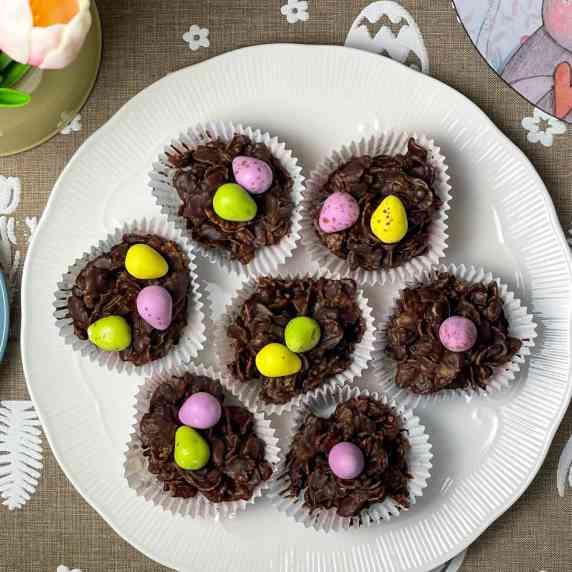A white plate of cornflake cakes with Easter table mat background with egg, flower images.