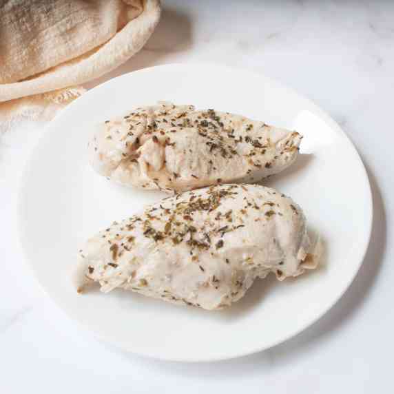 Chicken breasts seasoned with an Italian seasoning blend on a white plate. 