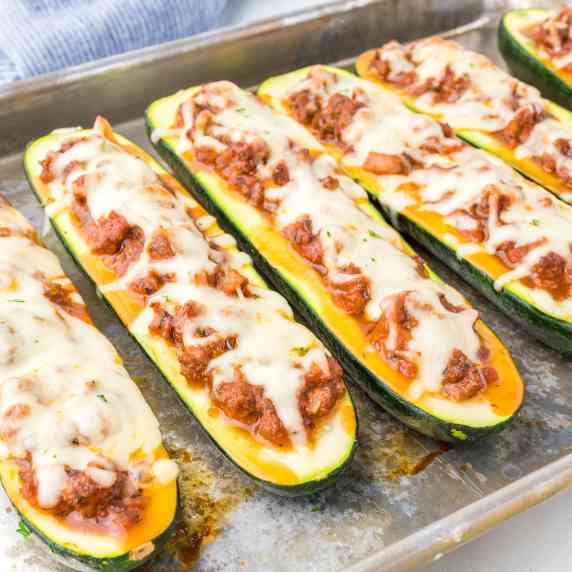 Close up of zucchini boats stuffed with ground beef and cheese on the pan.
