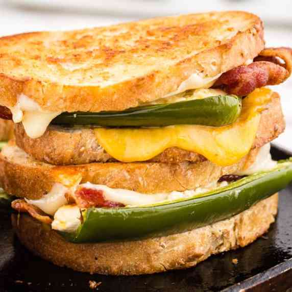 Jalapeno Popper Grilled Cheese sandwiches stacked together over a black marble kitchen top