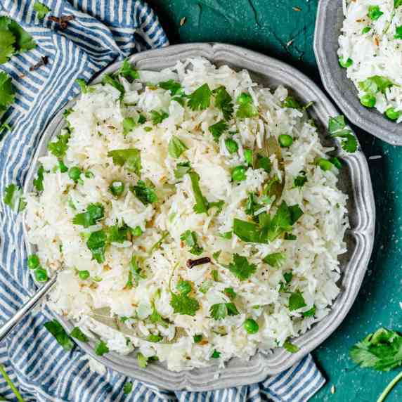 Garnishing plate of jeera rice with cilantro.