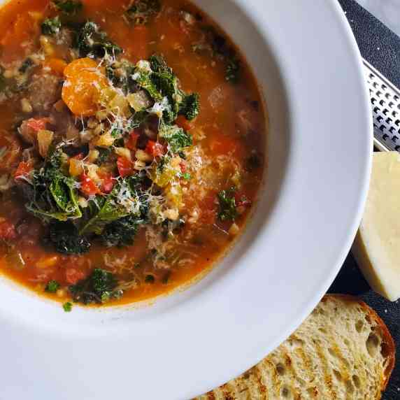 A comforting bowl of kale & barley soup, finished with a drizzle of EVOO & grana padano.