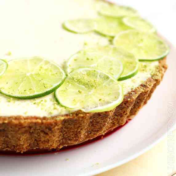 Keto Key lime pie cheesecake with Graham cracker crust, decorated with thin slices of lime.