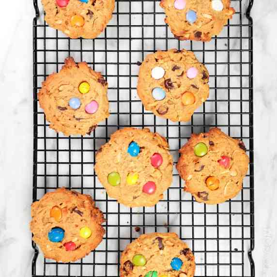 Baked monster cookies with M&M's on cooling rack.