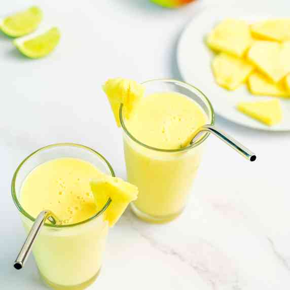 A closeup picture of the healthy mango smoothie in two tall glasses.