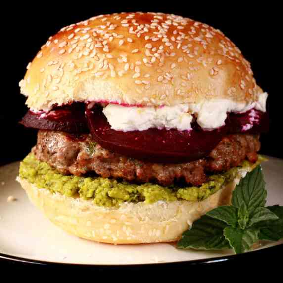 A moroccan spice lamb burger with beet slices, pea hummus, and goat cheese.