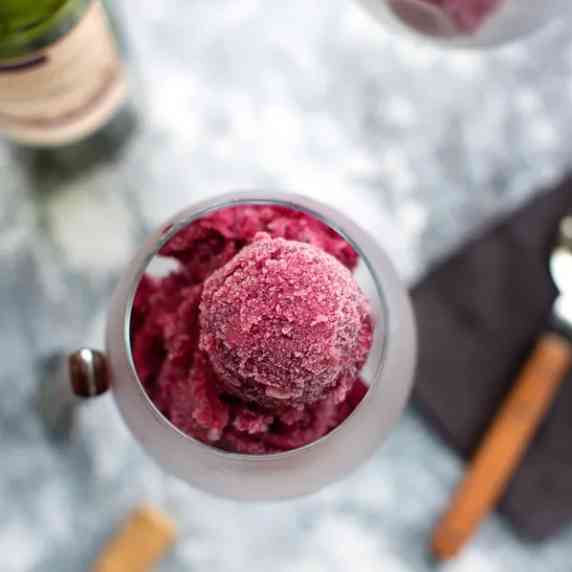 A wine glass with scoops of sorbet inside.