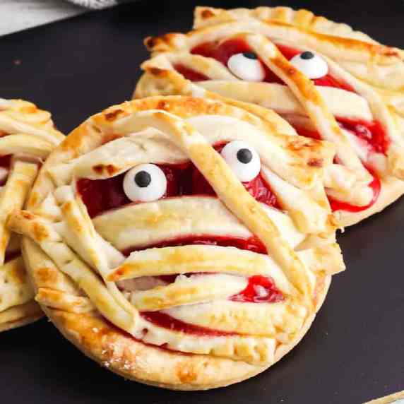 Close up of two cherry hand pies decorated like mummies.