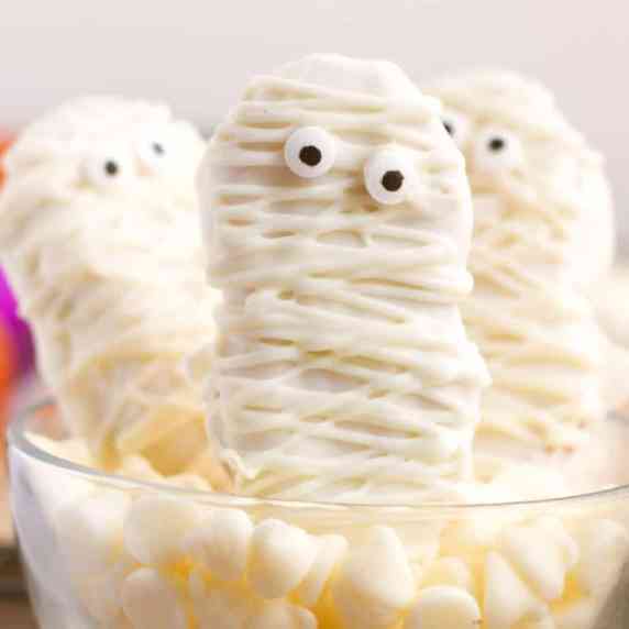 Three nutter butter cookies decorated with white chocolate to look like mummies in a serving bowl.