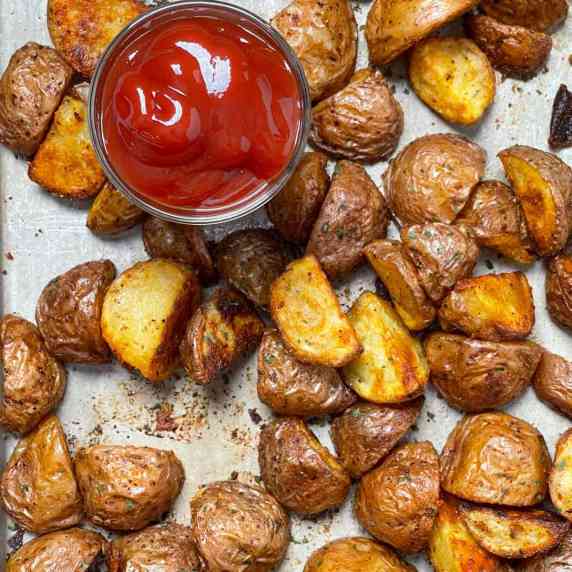 Crispy potatoes that were sliced in half and baked until golden brown with ketchup to dip them in.