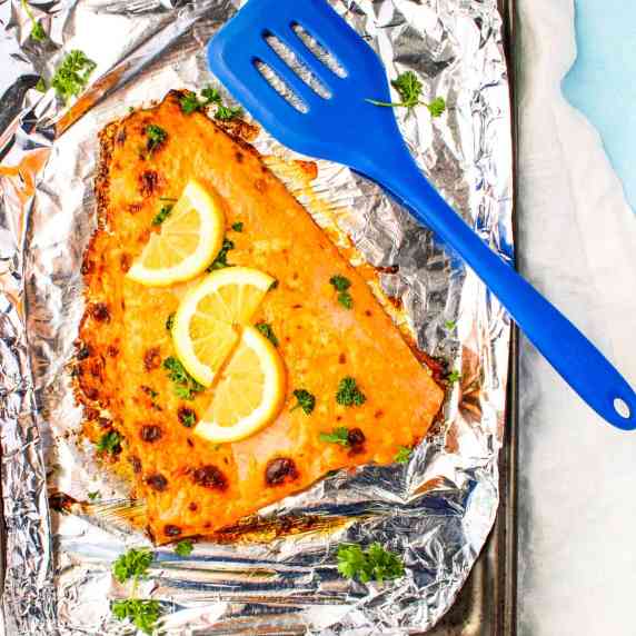 A large salmon filet on a tinfoil covered pan.