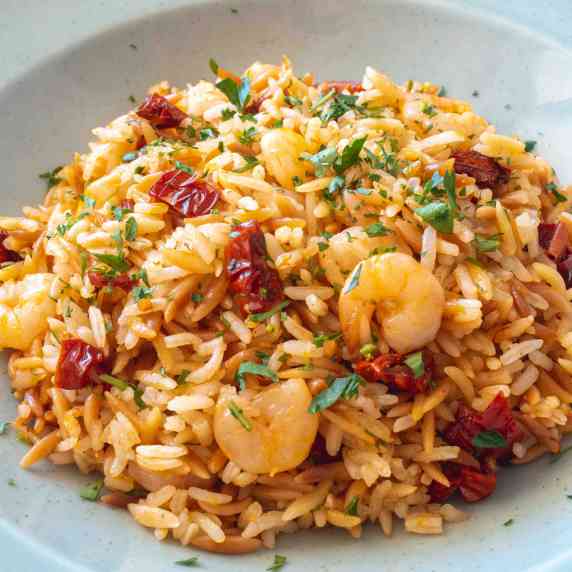close of orzo rice mixed with sun dried tomatoes, parsley and sultanas