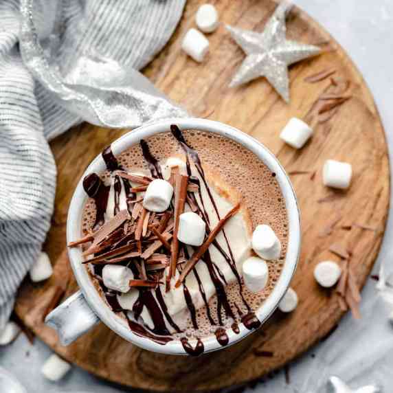 Peppermint hot chocolate in a mug with whipped cream, marshmallows and chocolate shavings.