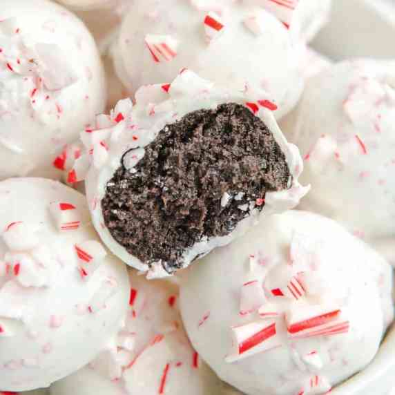 Peppermint Oreo Balls stacked with one missing a bite that shows chocolate inside the white outside 