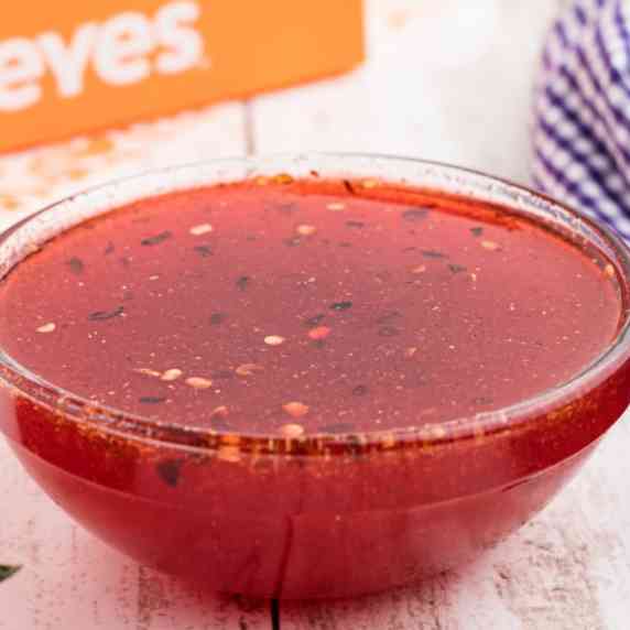 Close up of a small bowl of sweet and spicy popeyes sweet heat sauce.
