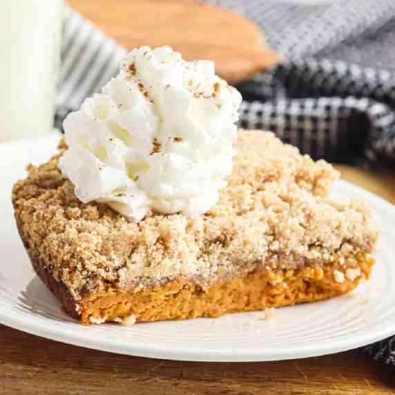 Up close layered pumpkin dump cake topped with whipped cream from the side.