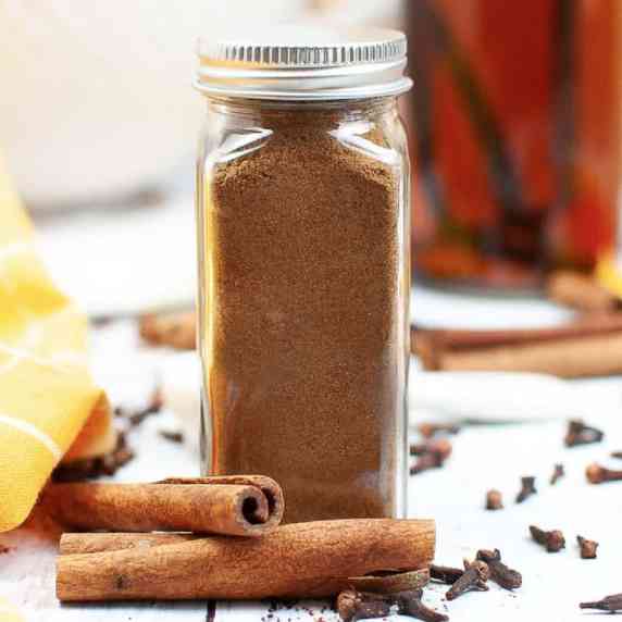 Pumpkin pie spice in a glass spice jar with a metal closed lid from the side.