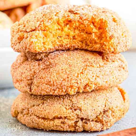 Pumpkin snickerdoodle cookies stacked with a bite out of the top cookie close up.