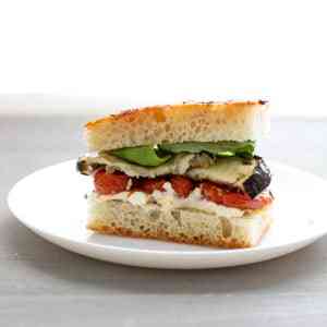 Close-up of a sandwich with soft focaccia, roasted eggplant, roasted tomatoes, garlic mayonnaise.