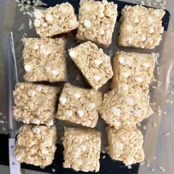 12 Large Homestyle Rice Cereal Treats arranged on parchment with serrated knife. 