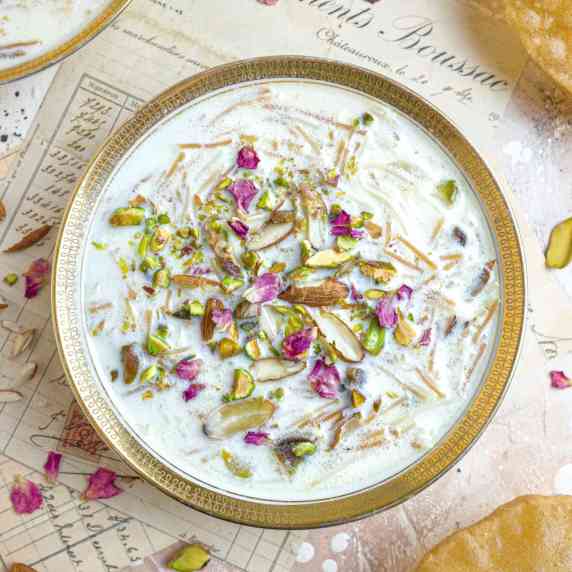 Seviyan kheer topped with rose petals in a white and gold bowl, on a vintage background.