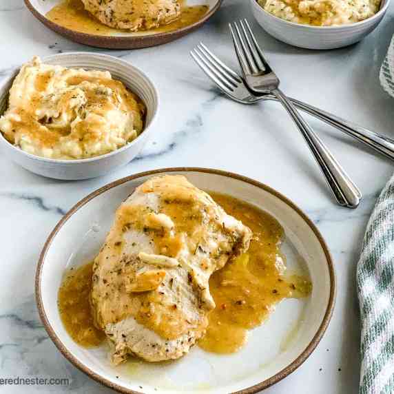 A plate of crock pot turkey tenderloin and a bowl of mashed potatoes with fork and dish towel