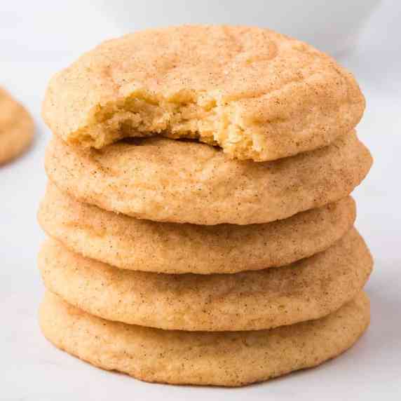 Stack of snickerdoodle cookies from the side on a white counter five cookies tall.