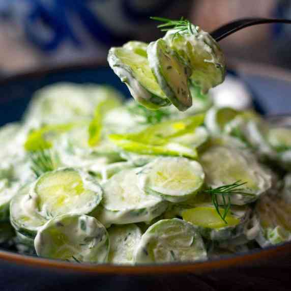 A few slices of cucumber picked up from a bowlful of Mizeria (Polish Cucumber Salad). 