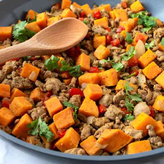 Sweet Potato Turkey Hash in a skillet with a wooden serving spoon.