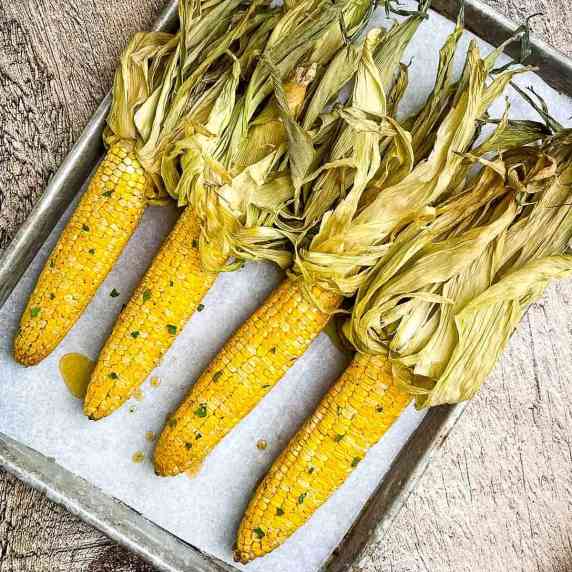 An overhead picture of smoked corn on the cob on a baking sheet.