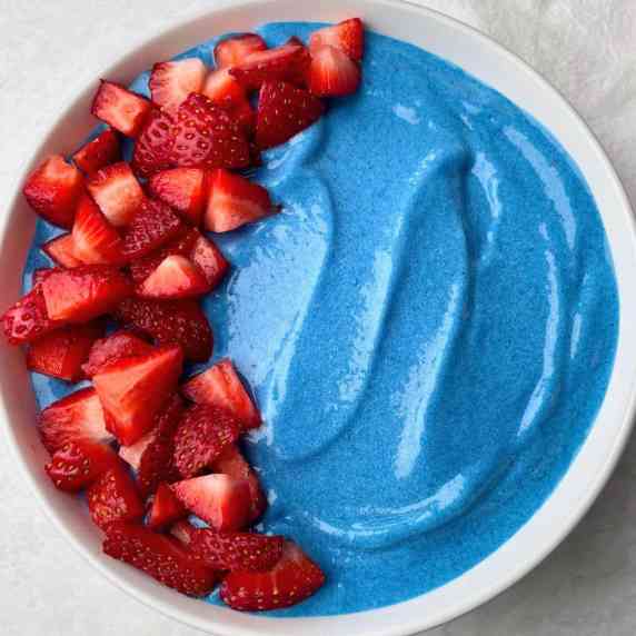 A blue spirulina smoothie bowl with strawberries.