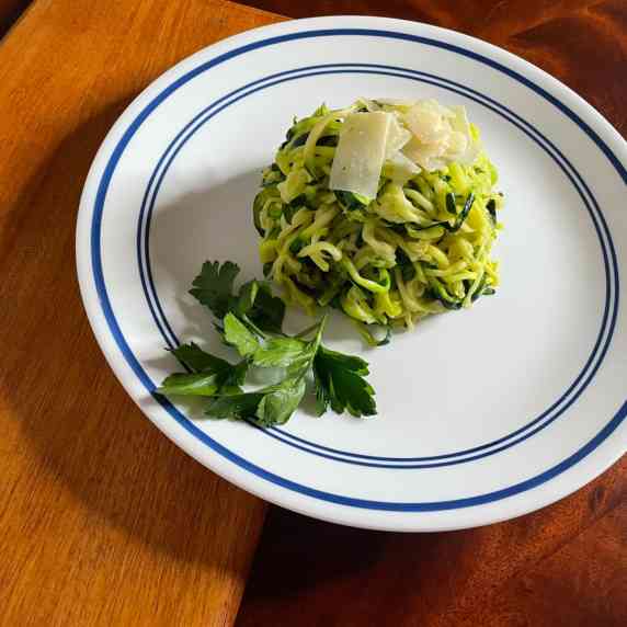 Zoodles with parmesan on a white plate.