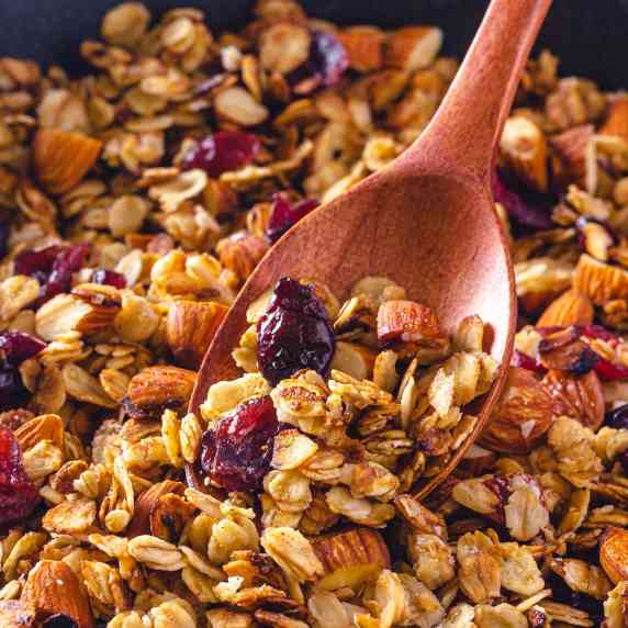 Granola with almonds and cranberries with a wooden spoon