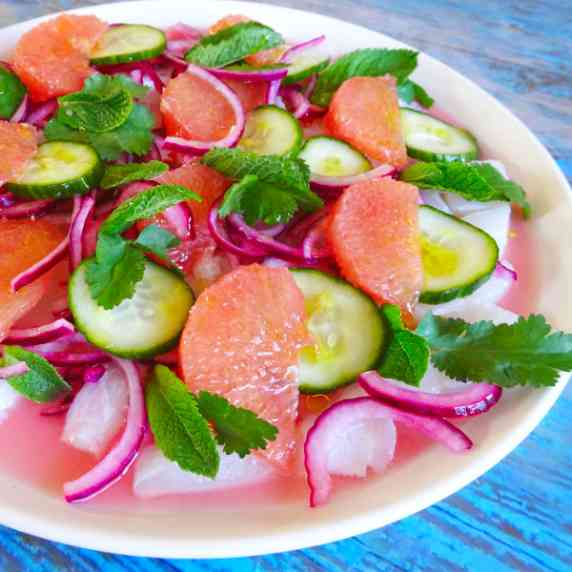 A large white plate sits filled with a colorful ceviche salad made of bacalao and pink grapefruit
