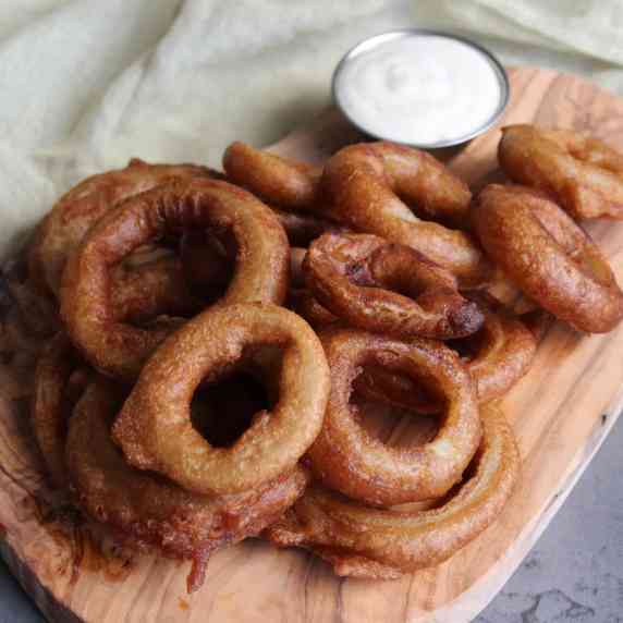 A plate of beer battered onion rings and ranch dressing.