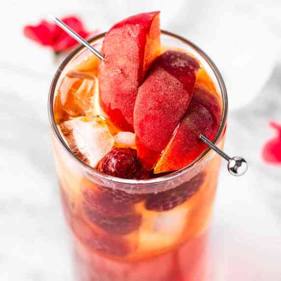 Overhead view of a bellini peach raspberry iced tea garnished with slices of fresh peaches.