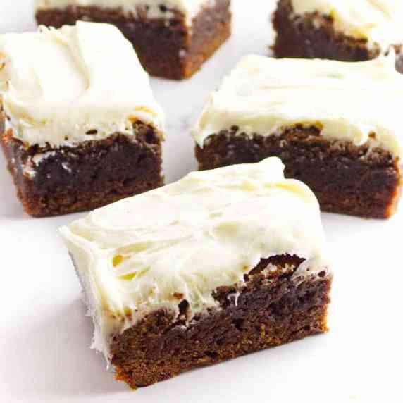 chocolate brownies with cream cheese frosting on a white background.