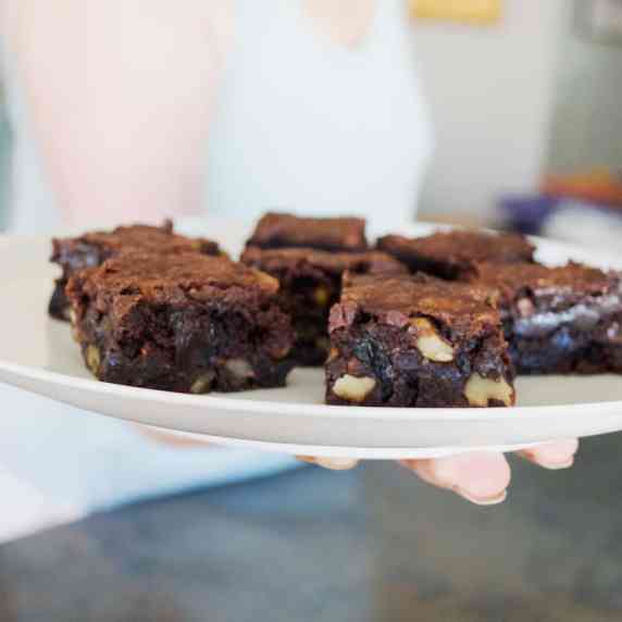 Closeup of a woman holding brownies on a white plate