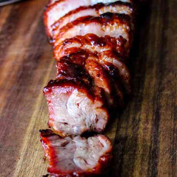 char siu sliced and placed on a wooden cutting board