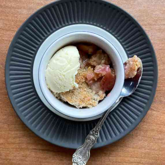small bowl of cherry crisp with scoop of vanilla ice cream and spoon.