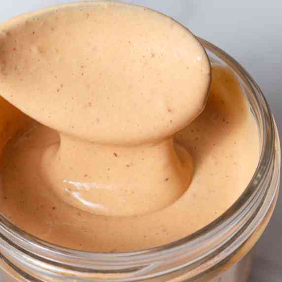 Spooning chipotle lime mayo aioli into a jar.