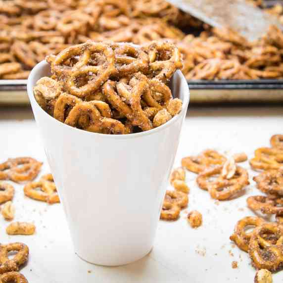Side angled view of cinnamon pretzels in a white ceramic cup with more pretzels in the background on