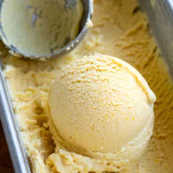 A single scoop of corn ice cream sitting in a metal ice cream container.