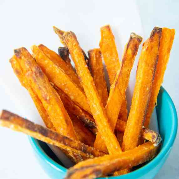 Crispy sweet potato fries in a teal bowl on a light background.