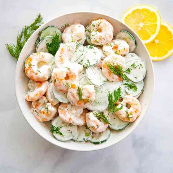 bowl of sliced cucumber and whole shrimp in a creamy dressing