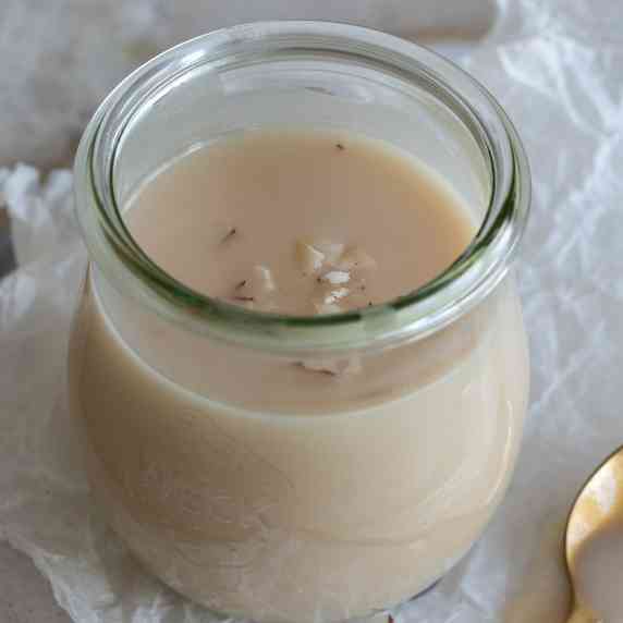 a small jar filled with white syrup and garnished with coconut flakes