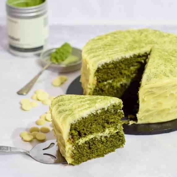 Easy matcha green tea cake sliced with white chocolate ganache frosting