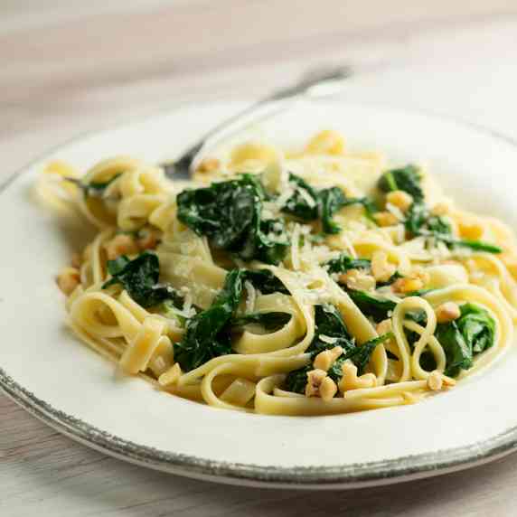 pasta with creamed spinach sauce on a plate with a fork