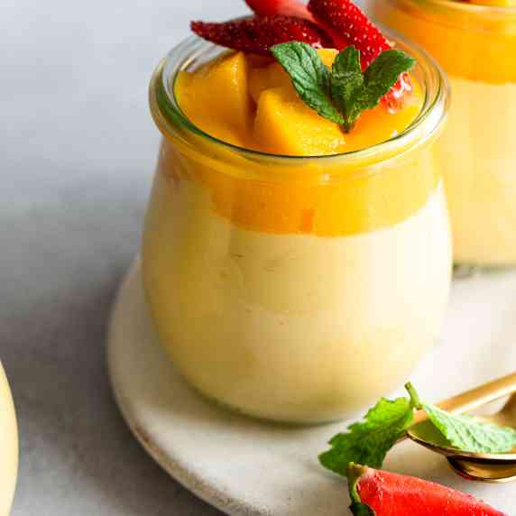 a small jar filled with mango mousse which is topped with more mango pulp